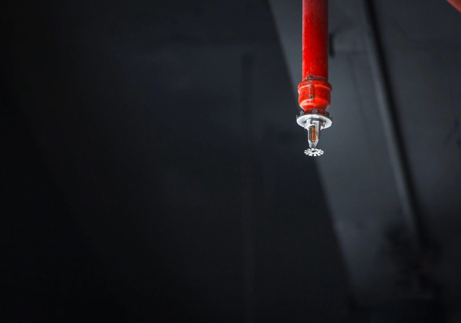 A red pipe hanging from the ceiling of an empty room.